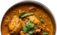 Chicken curry topped with coriander in a copper balti dish
