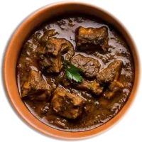 Dark meat curry with a sprig of coriander in a terracotta pot