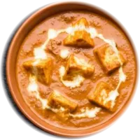 Paneer cubes in orange tomato gravy with a swirl of cream, in a terracotta pot
