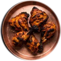 Charred tandoori chicken pieces on a copper plate