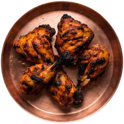 Charred tandoori chicken pieces on a copper plate